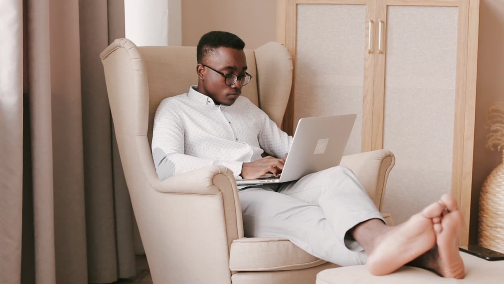 A man working on a laptop in an armchair