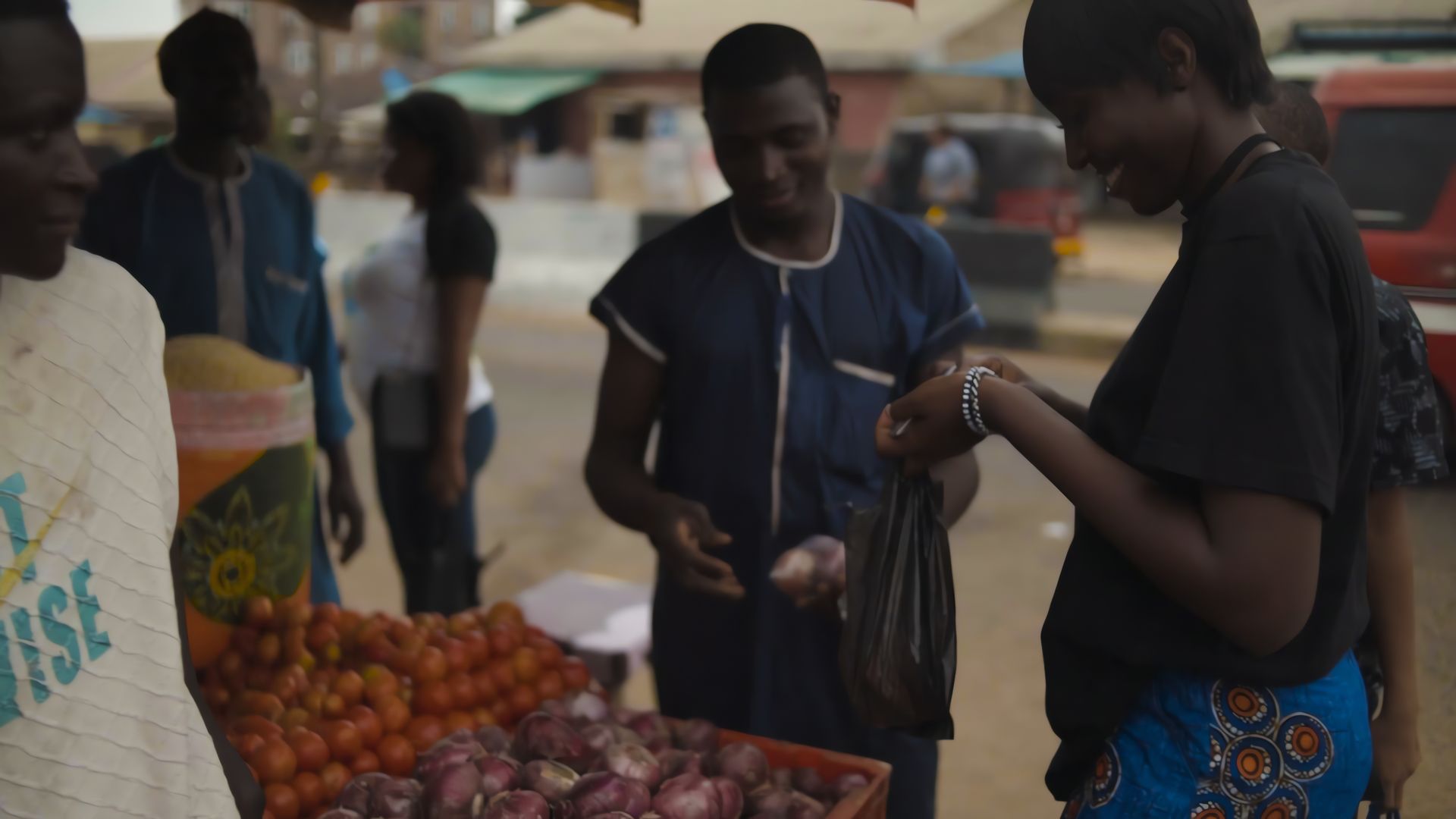 A customer and traders exchanging goods at a market stall