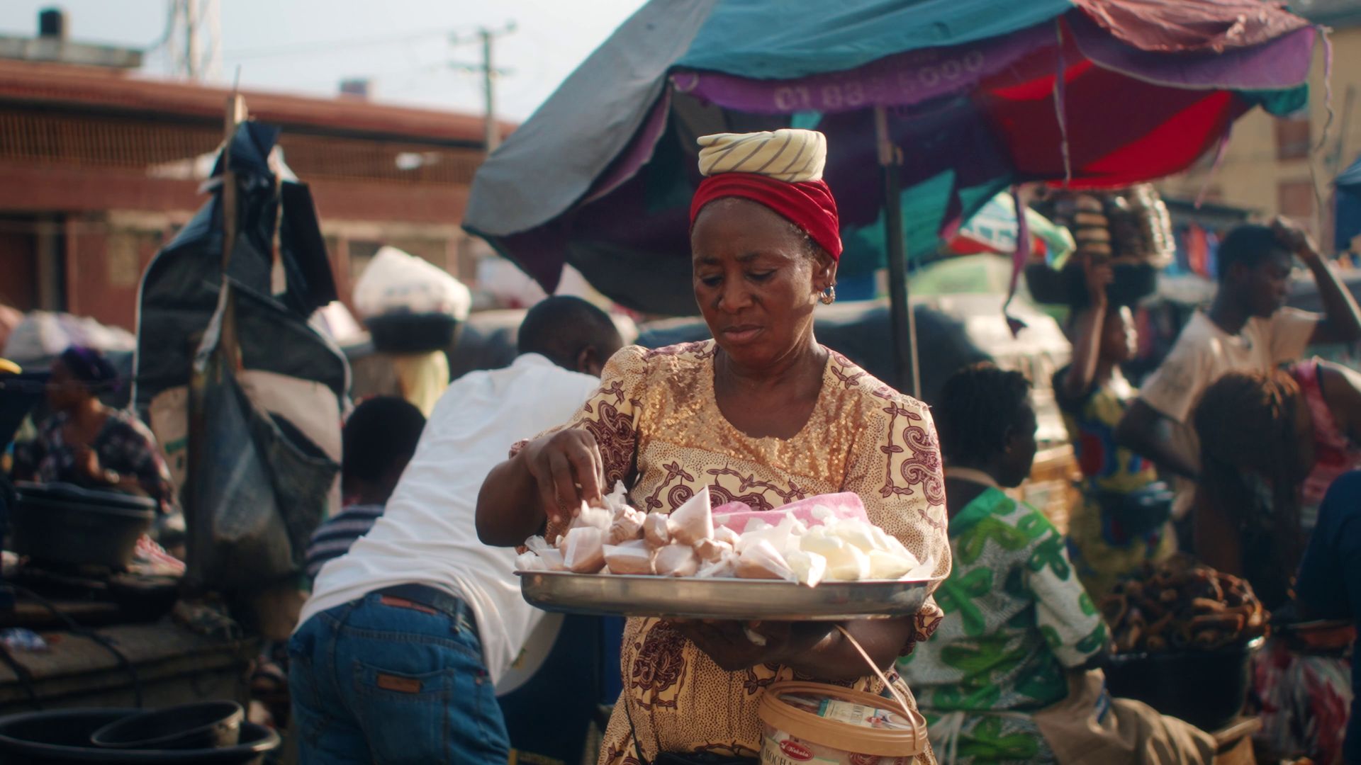 A trader arranging goods at a busy outdoor market