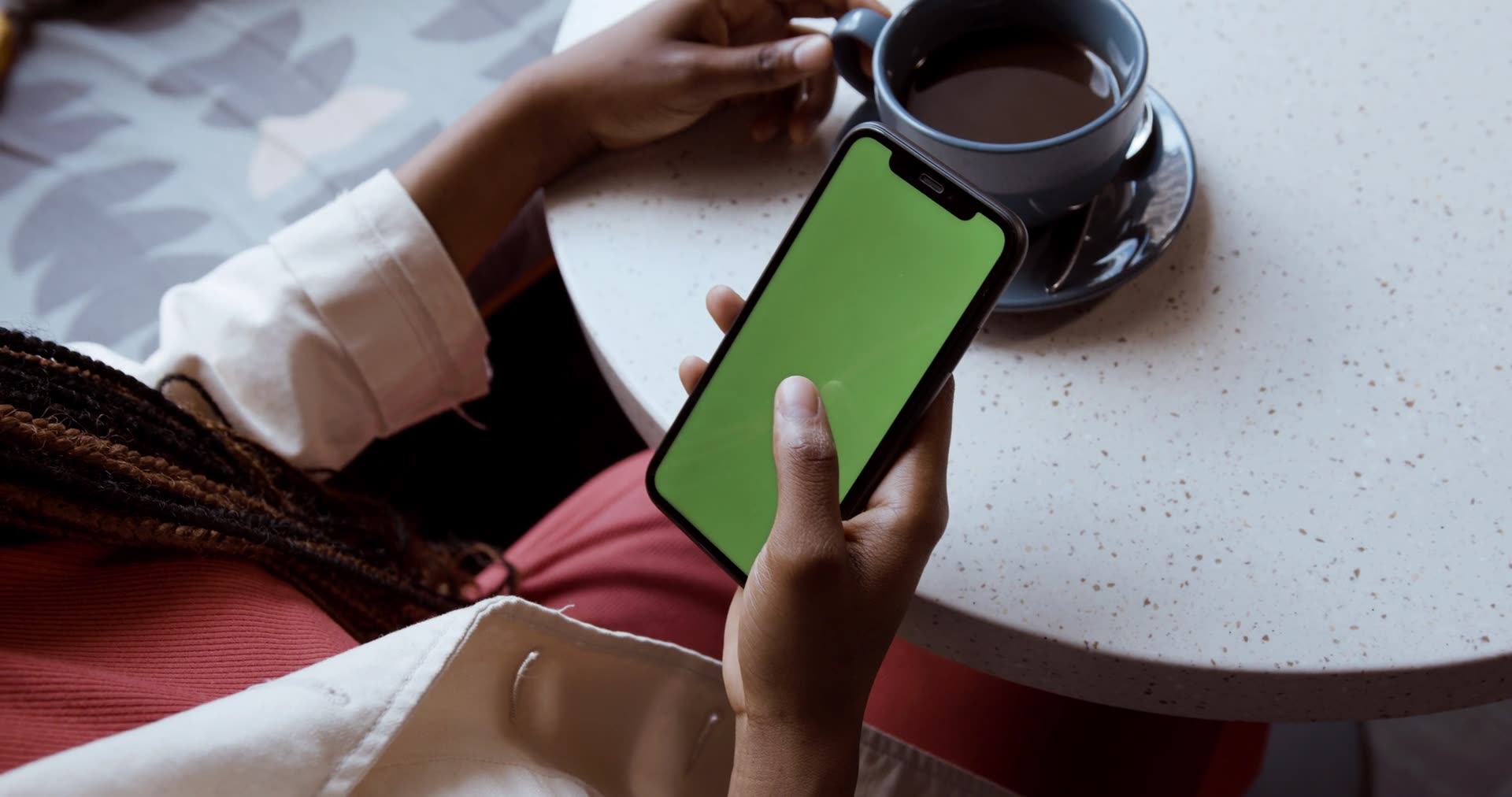 A person holding a phone at a cafe table