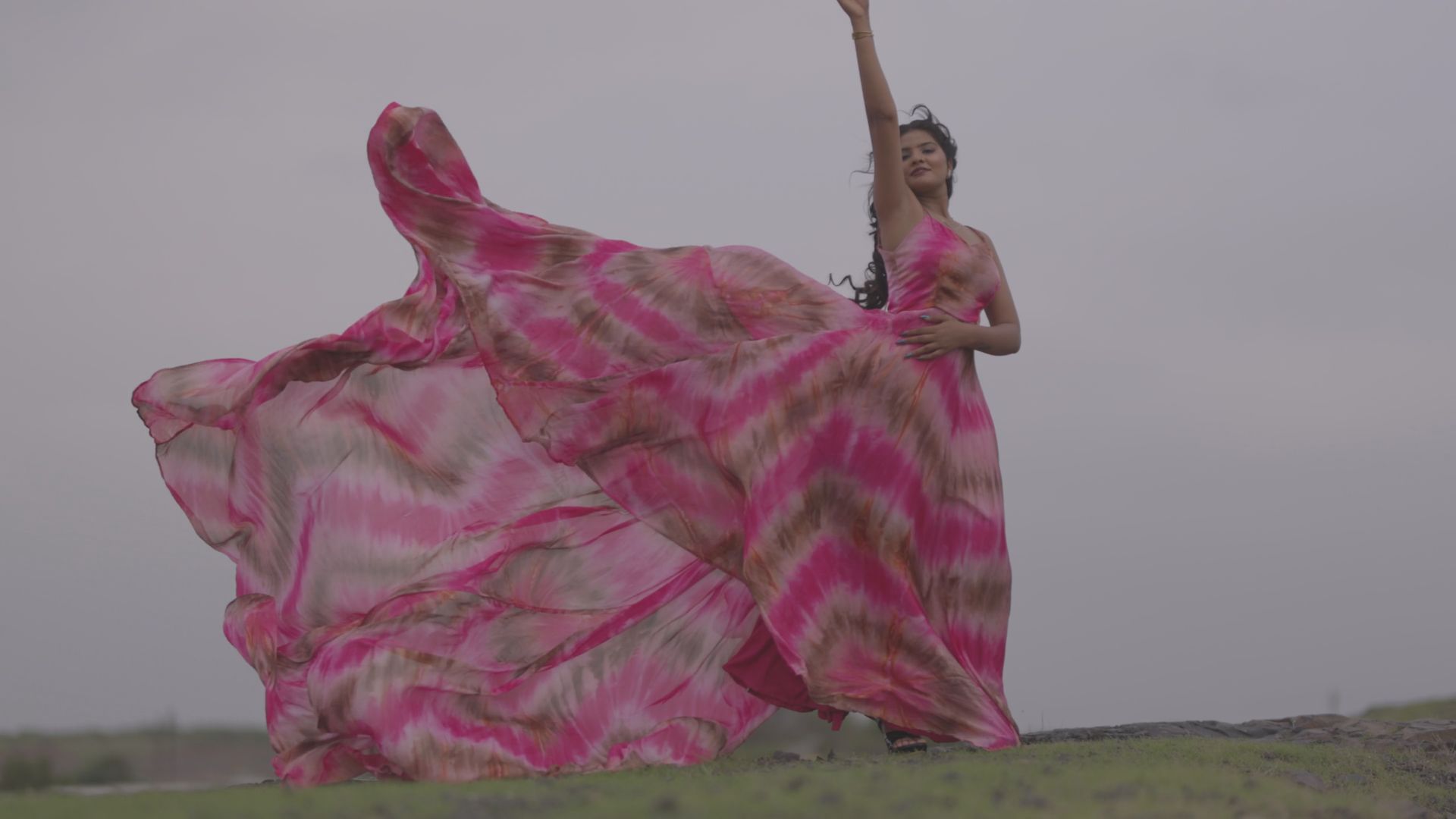 A model in a pink dress blowing in the wind