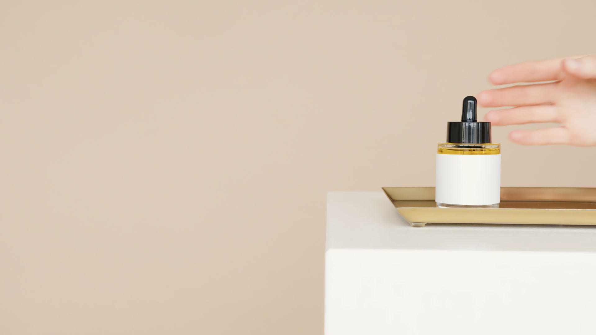 A skincare bottle being placed on a plinth